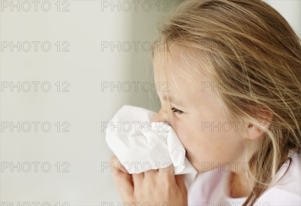 Girl (10-11) blowing nose. Photo : Momentimages