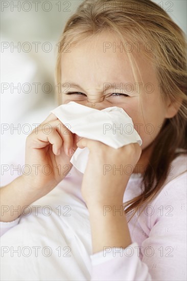 Girl (10-11) blowing nose. Photo : Momentimages