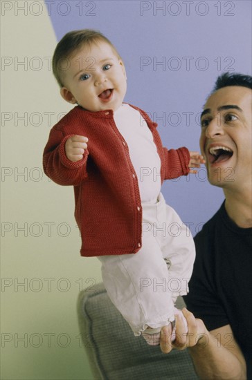 Baby standing on father's hand. Photo : Fisher Litwin