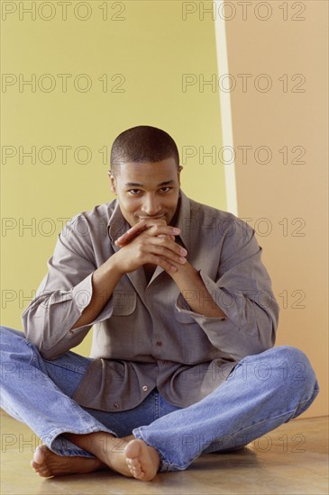 Handsome man sitting cross legged. Photo : Fisher Litwin
