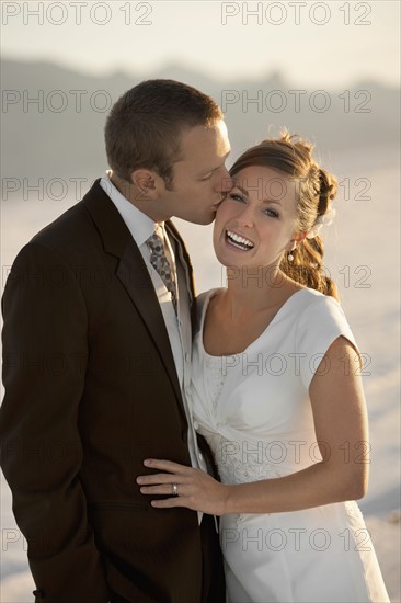 Groom kissing bride in desert. Photo : FBP