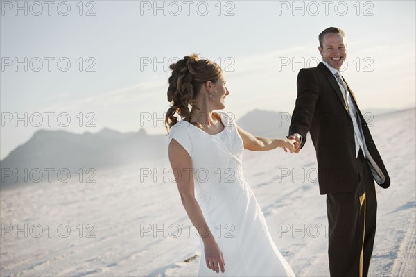 Bride and groom holding hands in desert. Photo : FBP