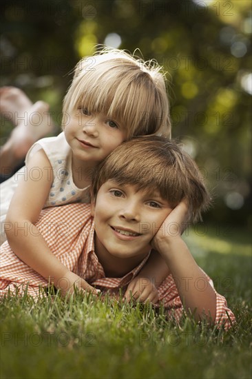Portrait of brother and sister (2-8-9) lying on grass. Photo : FBP