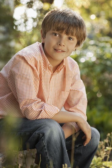 Portrait of boy (8-9) sitting in garden. Photo : FBP