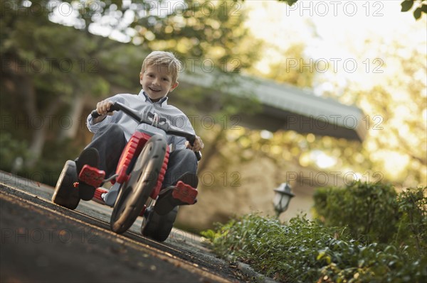 Portrait of boy (6-7) riding tricycle. Photo : FBP