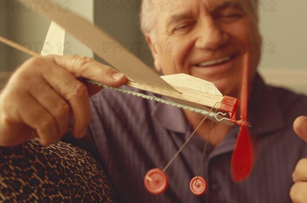 Senior man playing with toy airplane. Photo : Fisher Litwin