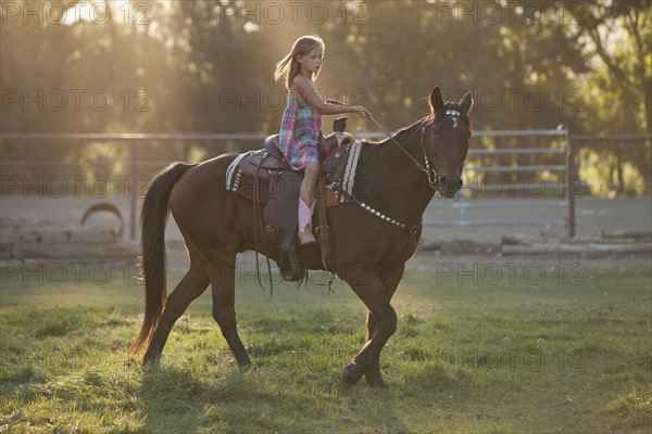 Girl (8-9) riding horse in paddock. Photo : Mike Kemp