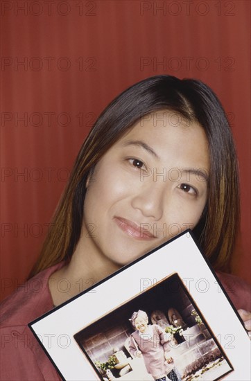 Young girl holding a photograph of her grandmother. Photo : Fisher Litwin