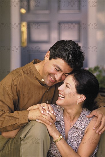 Happy couple sitting in front of their home. Photo : Fisher Litwin