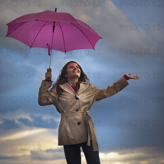 Young woman with umbrella under overcast sky. Photo : Mike Kemp