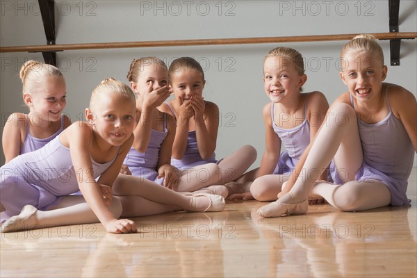 Portrait of female ballet dancers (6-8) sitting in dance studio. Photo : Mike Kemp