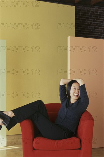 Woman relaxing in red chair. Photo : Fisher Litwin
