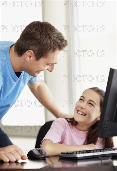 Father with daughter (10-11) playing with computer. Photo : Momentimages