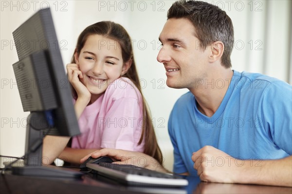 Father with daughter (10-11) playing with computer. Photo : Momentimages