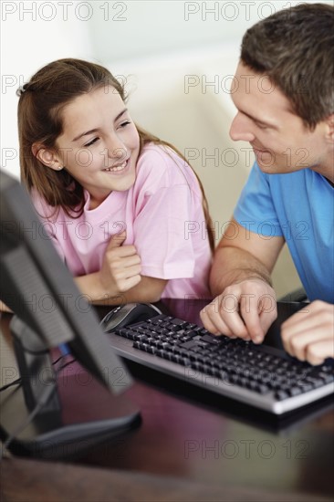Father with daughter (10-11) playing with computer. Photo : Momentimages