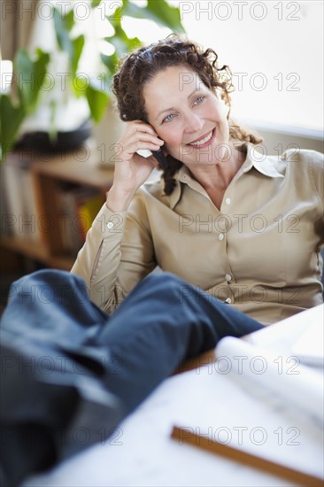 Architect working in studio, using mobile phone. Photo : Take A Pix Media