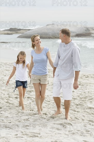 Girl (10-11) playing on beach with parents. Photo : Momentimages