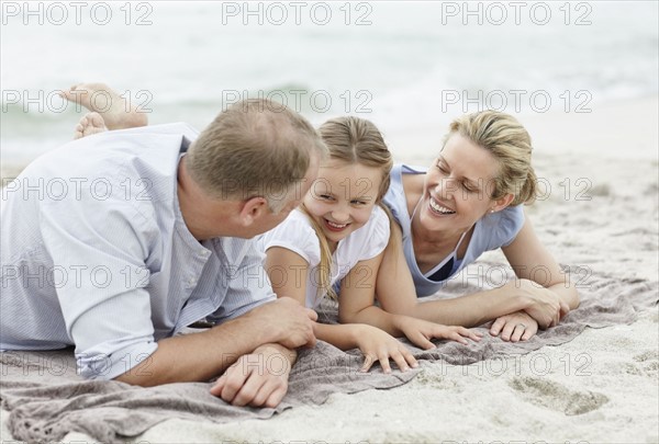 Girl (10-11) playing on beach with parents. Photo : Momentimages