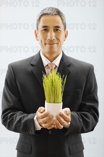 Studio portrait of young man holding wheat grass. Photo : FBP