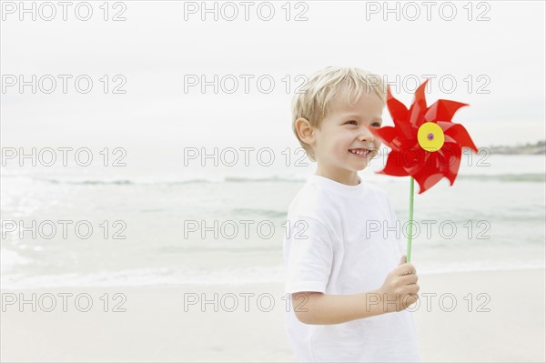 Boy (4-5) holding red pinwheel. Photo : Momentimages