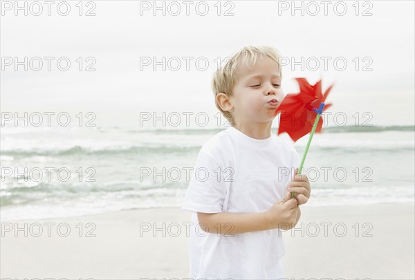 Boy (4-5) blowing on red pinwheel. Photo : Momentimages