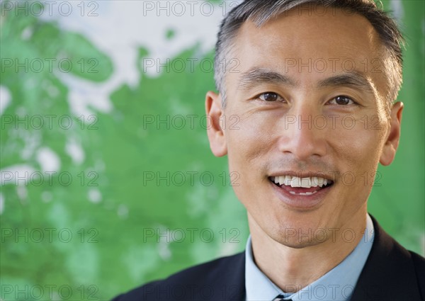 Portrait of businessman looking at camera and smiling, studio shot. Photo : Jamie Grill