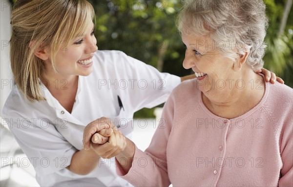 Daughter with mother holding hands and looking each other. Photo : Momentimages