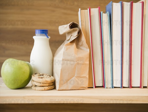 Row of books and lunch bag on shelf. Photo : Jamie Grill