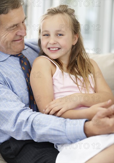 Smiling grandfather and granddaughter (10-11). Photo : Momentimages