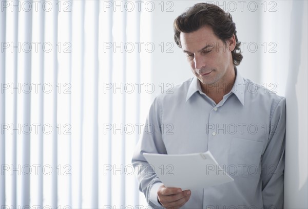 Man in office reading document.