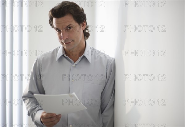 Man in office holding document.