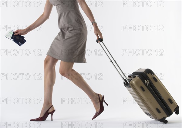 Young woman with suitcase, studio shot.