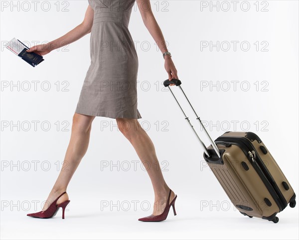 Young woman with suitcase, studio shot.