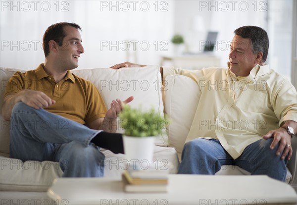 USA, New Jersey, Jersey City, Father and son talking on sofa in living room.