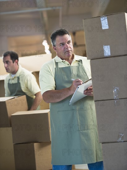 USA, New Jersey, Jersey City, Two male warehouse workers by stacked boxes.