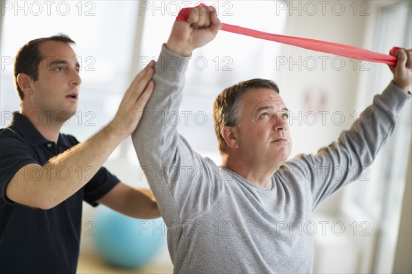 USA, New Jersey, Jersey City, Fitness instructor assisting man in gym.