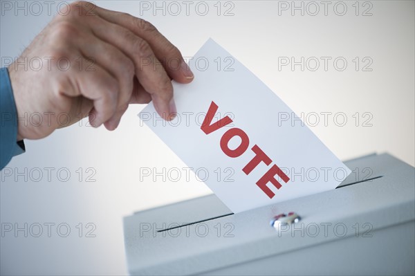 Man putting vote card into box.