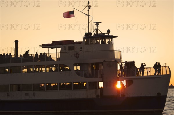 USA, New York City, Silhouette of passengers on tourboat.