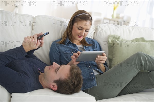 USA, New Jersey, Jersey City, Portrait of young couple relaxing on sofa.