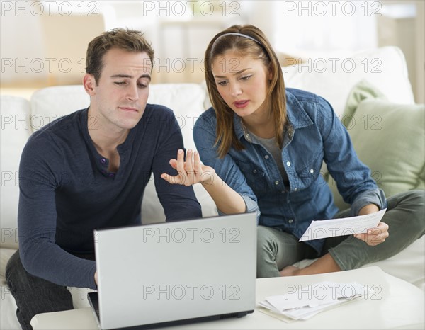 USA, New Jersey, Jersey City, Portrait of young couple doing paperwork at home.