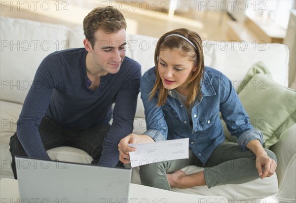 USA, New Jersey, Jersey City, Portrait of young couple doing paperwork at home.