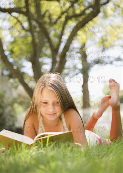 USA, New York, Girl (10-11) reading book in park. Photo : Jamie Grill Photography