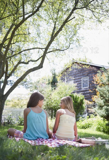 USA, New York, Two girls (10-11, 10-11) sitting on blanket in backyard. Photo : Jamie Grill Photography