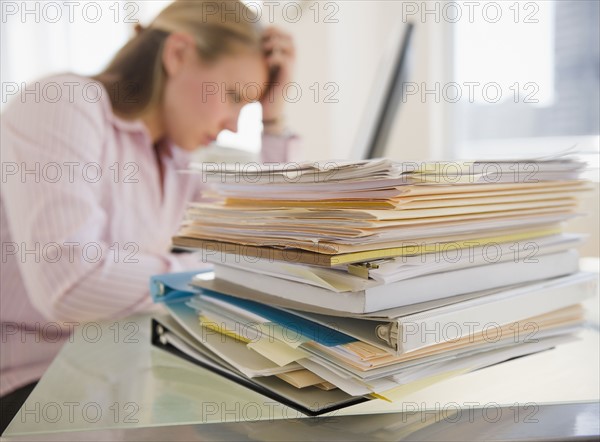 USA, New Jersey, Jersey City, Stressed young businesswoman doing paperwork. Photo : Jamie Grill Photography