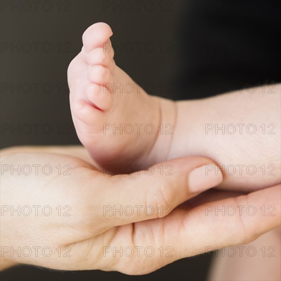 USA, New Jersey, Jersey City, Close-up view of mother's hand holding baby daughter leg (2-5 months). Photo : Jamie Grill Photography