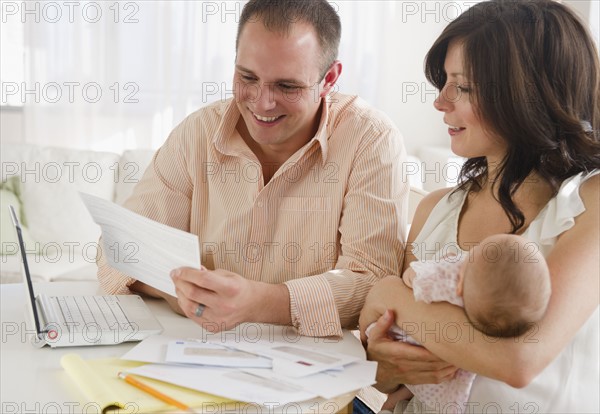 USA, New Jersey, Jersey City, Family with baby daughter (2-5 months) reading correspondence. Photo : Jamie Grill Photography