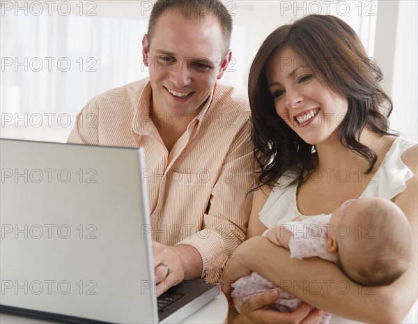 USA, New Jersey, Jersey City, family with baby daughter (2-5 months) sitting in front of laptop. Photo : Jamie Grill Photography