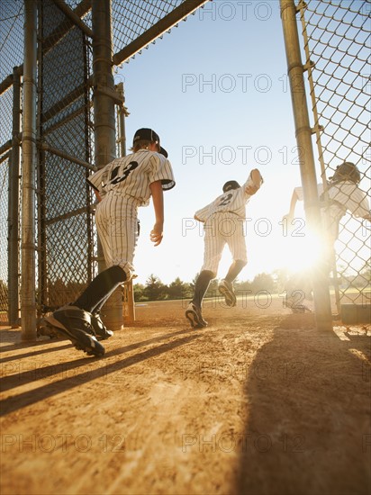 Baseball players (10-11) entering baseball diamond.