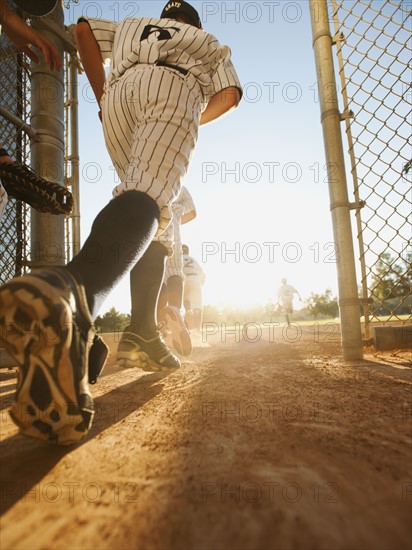 Baseball players (10-11) entering baseball diamond.