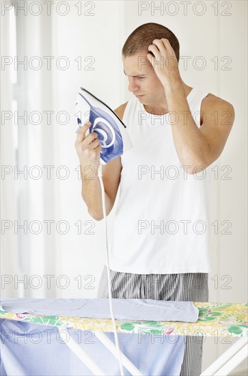 South Africa, Young man confused while holding iron. Photo : momentimages